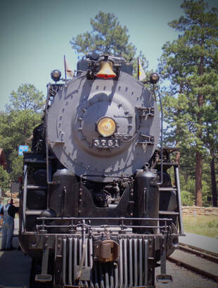 Front of a large steam locomotive. Centered headlight is centered with the numbers 3751 written in silver below. Brass Bell and lanterns are on the top of the engine. 