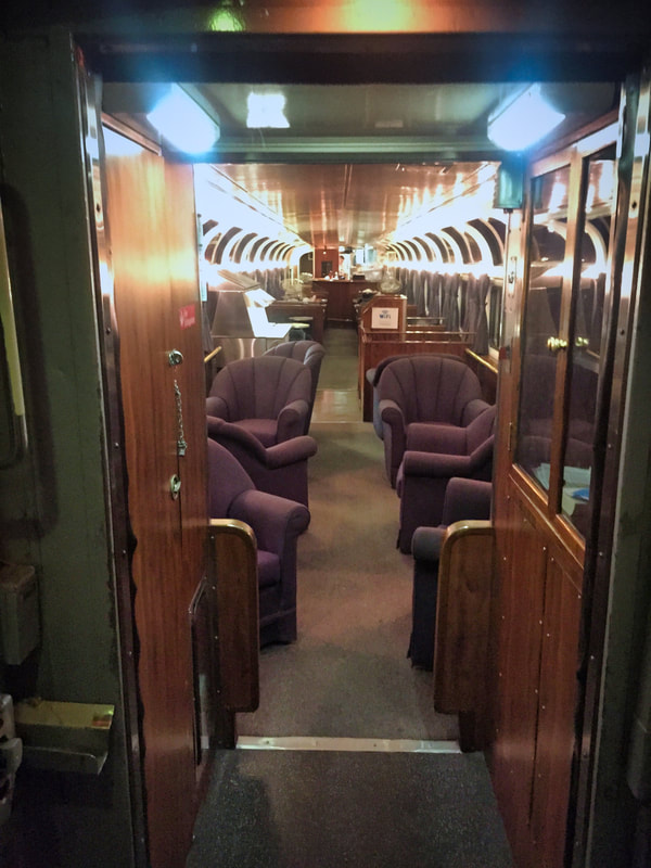 As you look into the Parlour car from one end you see purple lounge chairs, and rows of double windows. 