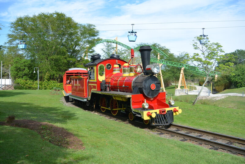 Red and Yellow Steam Locomotive. Skyway and rollercoaster in the background. 