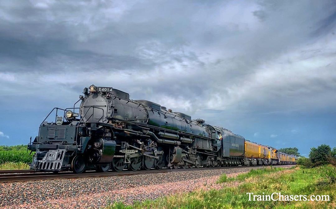 Large Steam Locomotive pulls a train of Yellow Coaches. 